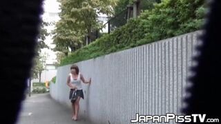 young Japanese girl urinates boldly on the pavement